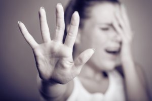 Woman holding out hand as if to ward someone off