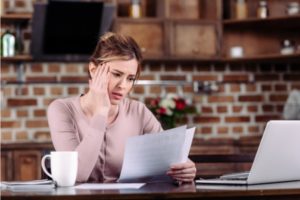 Woman with pink shirt looking distressed at the divorce papers she's holding